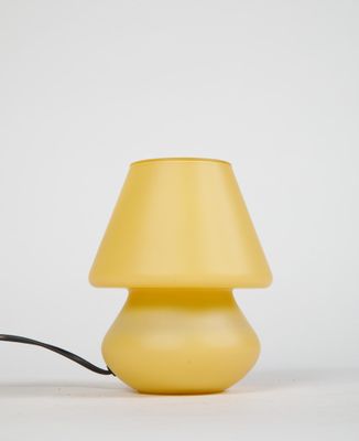 lampe de table jaune avec un cordon noir posée sur une surface blanche