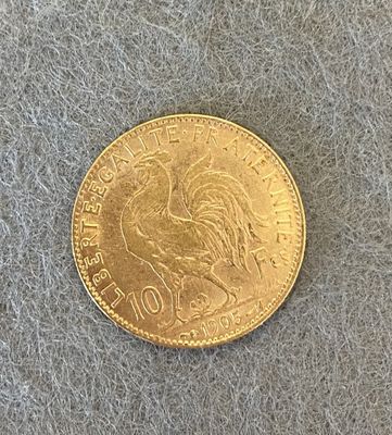 une pièce d'or représentant un coq sur un fond gris