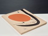 une peinture abstraite orange et noire posée sur une table blanche