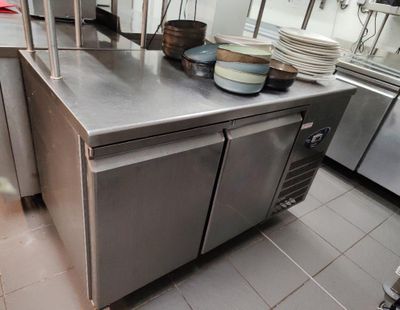 plan de travail en acier inoxydable dans une cuisine commerciale avec des casseroles et des poêles dessus