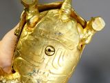 Quelqu'un tient dans sa main un objet en forme de tortue en or.