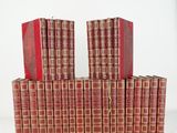 plusieurs livres rouges empilés les uns sur les autres sur une surface blanche