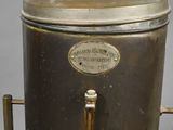 a metal container with a brass handle on a stand