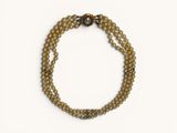 un gros plan d'un bracelet en perles posé sur une surface blanche