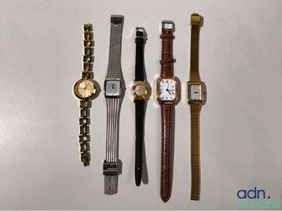 quatre montres différentes sont alignées sur une surface blanche
