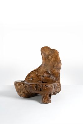 sculpture en bois représentant un chien tenant un bol dans la gueule, posée sur une surface blanche