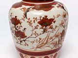 a red and white vase sitting on a white surface