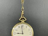 a close up of a gold pocket watch on a chain