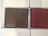 four leather wallets in a box on a white surface