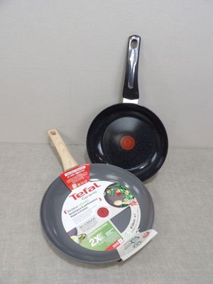 deux casseroles et une poêle posées sur une table