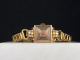 une image d'une montre-bracelet en or sur une surface blanche
