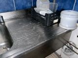 a metal sink with a basket of dishes on top of it