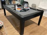 une table de billard au milieu d'une pièce, sur laquelle est posé un ordinateur portable