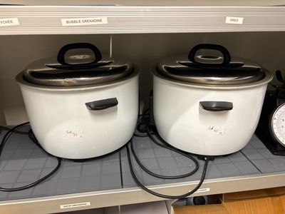 two crock pots sitting on a shelf next to a clock