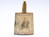 une flasque ancienne en laiton sur laquelle figure l'image d'un homme à cheval
