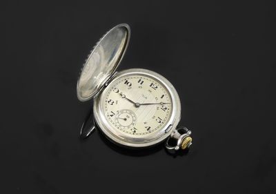 an old silver pocket watch sitting on top of a black surface