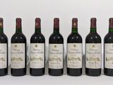 six bouteilles de vin sont alignées sur une surface blanche