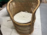 une chaise en osier avec un coussin posé dessus, dans un magasin