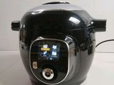 a black and silver electric pressure cooker on a table