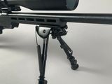 a close up of a rifle on a tripod with a scope