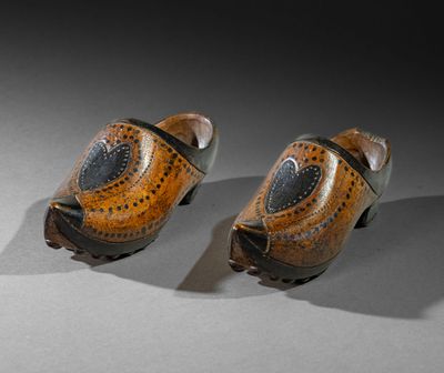 pair of wooden shoes with holes on them sitting on a table