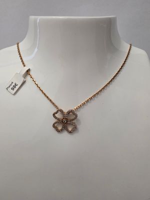 un collier en or orné d'un pendentif en forme de nœud, porté par un mannequin