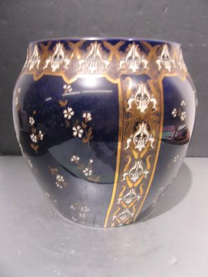 un vase bleu orné de motifs dorés, posé sur une table