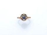 gros plan d'une bague en or avec un saphir et des diamants