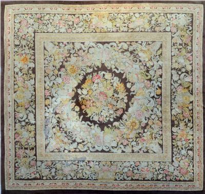 an antique rug with a floral design on a brown ground