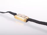 an image of a wrist watch with a gold clasp on a black rope