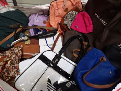 a pile of purses and handbags sitting on a bed