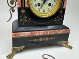 a black and gold clock on a stand with a key