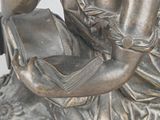 a statue of a woman reading a book on a rock