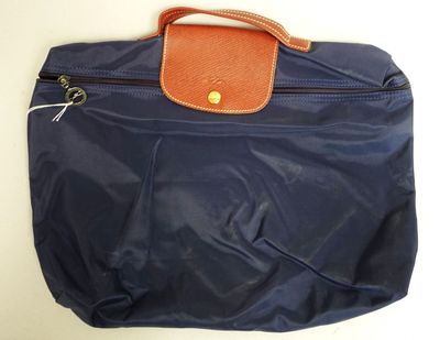 un sac bleu muni d'une poignée marron posé sur une table blanche