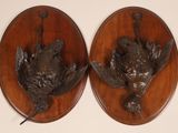 paire de têtes d'oiseaux en bronze fixées sur des plaques en bois accrochées au mur