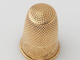 a gold thimble on a white background