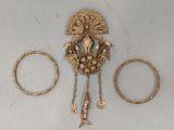 three gold rings and a broochet on a white surface