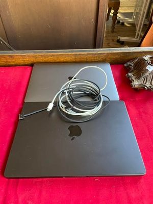 an apple macbook pro laptop with a charger and cable on a red surface