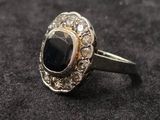 gros plan d'une bague avec une pierre noire entourée de diamants blancs