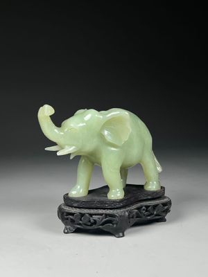 une petite statue d'éléphant verte posée sur un socle noir
