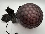 a purple glass ball on a white surface with a black cord