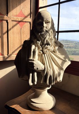 une statue représentant un homme assis sur une table devant une fenêtre