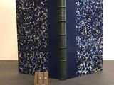 an old book with a blue cover sitting on top of a table