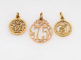 three gold pendants with the number 75 on them