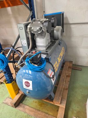 un compresseur d'air bleu posé sur une palette dans un garage