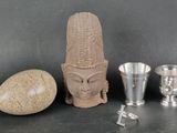 a statue of a head, a vase, and a rock on a table