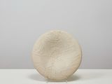 a white vase sitting on top of a table next to a white wall