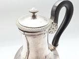 an antique silver tea pot with a black handle on a white surface