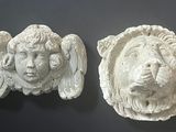 two white sculptures of a lion and a lion ' s head on a wall