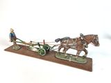 a figurine of a horse pulling a cart with a man on it